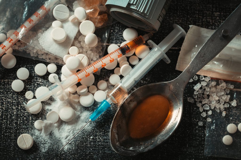 A table displaying drugs, pills, and a spoon, symbolizing drug-related items and paraphernalia