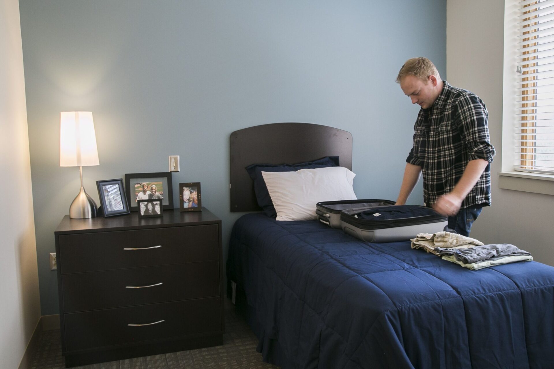 A man carefully arranging his clothes inside a suitcase