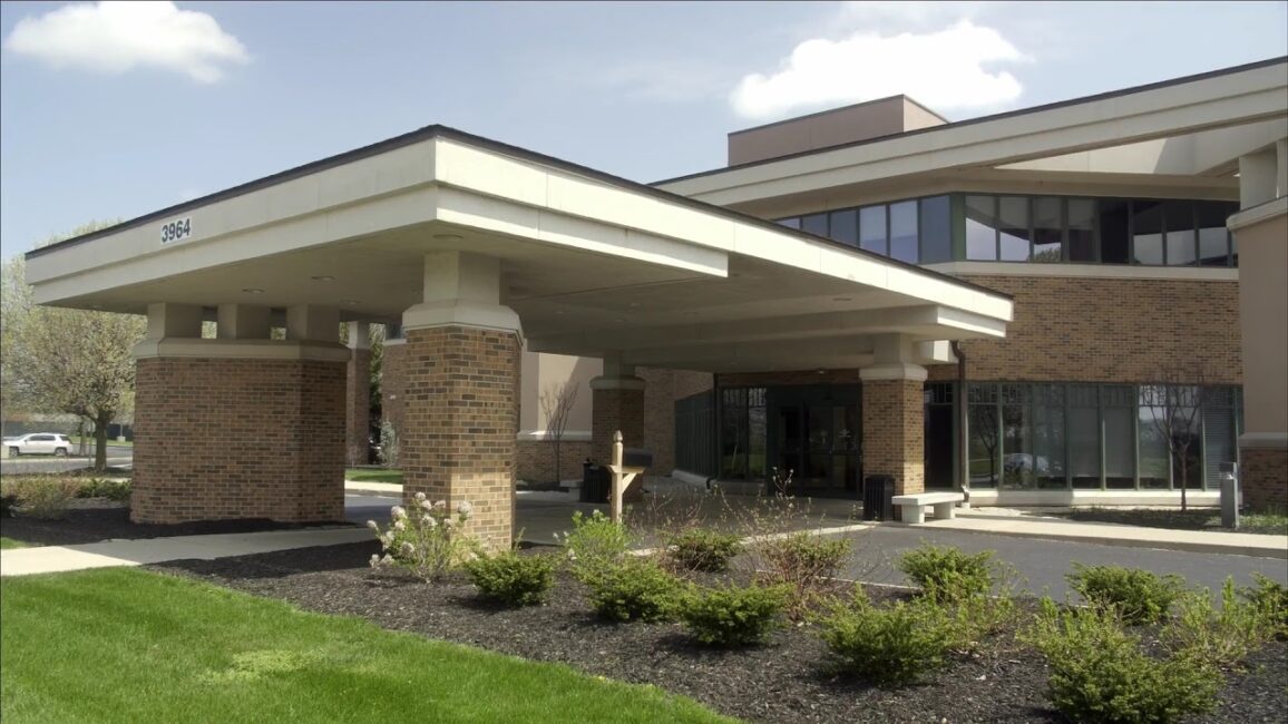 Facility building with modern architecture and glass windows, surrounded by lush greenery